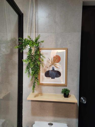 a bathroom with a picture and a plant on a shelf at One-Bedroom and Studio Apartment near SM City , IT Park and Ayala Mall - NO PARKING at Bamboo Bay Community in Mandaue City