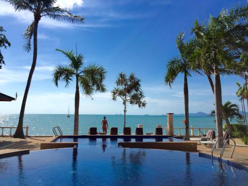 a person standing next to a swimming pool next to the ocean at Samui Mermaid Beachfront in Bang Rak Beach