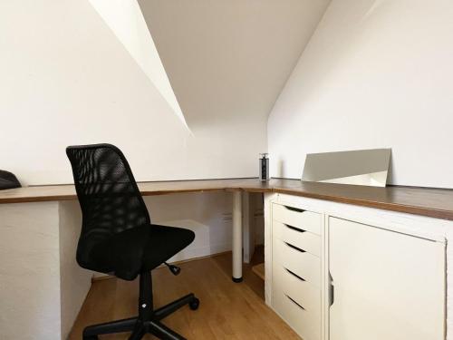 un bureau mansardé avec un bureau et une chaise dans l'établissement Le Panorama Chartrain, à Chartres