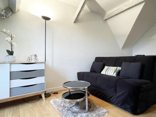 un salon avec un canapé noir et une table dans l'établissement Le Panorama Chartrain, à Chartres