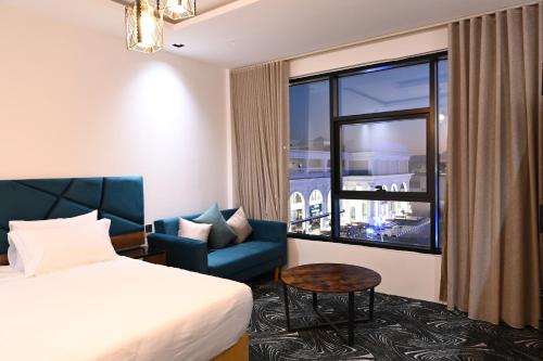 una camera d'albergo con un letto, una sedia e una finestra di SUN SET HOTEL فندق سن ست a Najran