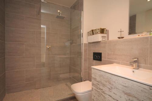 a bathroom with a shower and a toilet and a sink at Ciudad de Elda Deluxe Apartment in Albir