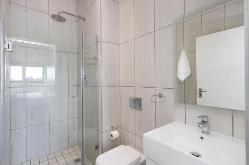 a bathroom with a shower and a toilet and a sink at Atlantic Port 9 in Bloubergstrand