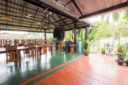 um restaurante com mesas e cadeiras de madeira num piso de madeira em OYO 920 Saensukkho Hotel And Resorts em Chiang Rai