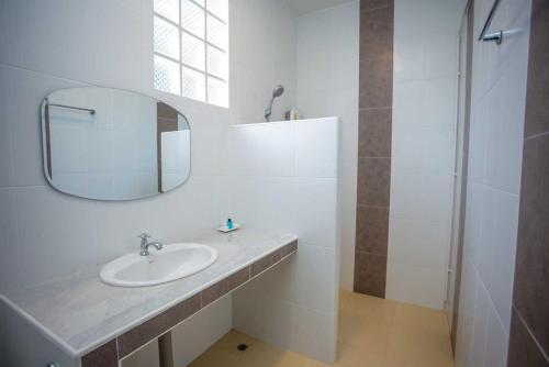 een witte badkamer met een wastafel en een spiegel bij OYO 75464 Nakarin Hotel in Amnat Charoen