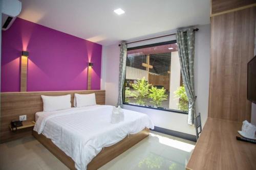 a bedroom with a bed and a purple wall at OYO 75464 Nakarin Hotel in Amnat Charoen