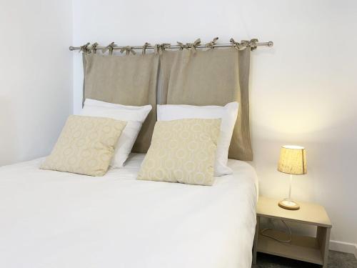 Schlafzimmer mit einem Bett mit weißer Bettwäsche und Kissen in der Unterkunft Le Matisse in Mainvilliers