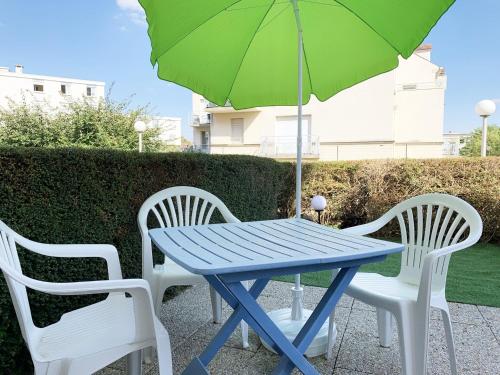 une table bleue avec deux chaises et un parasol vert dans l'établissement Le Matisse, à Mainvilliers
