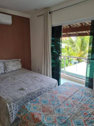 a bedroom with a bed and a large window at Praia de Jaúa, Piscina privativa, churrasqueira. in Camaçari