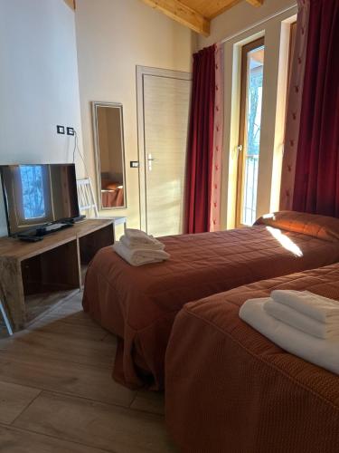 チェザーナ・トリネーゼにあるHotel Chalet Casa Cesanaのベッド2台とテレビが備わるホテルルームです。