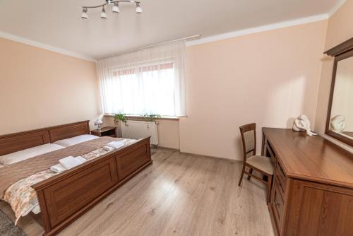a bedroom with a bed and a desk and a window at Hotel Skaut in Chorzów