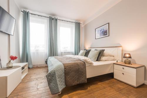 a white bedroom with a bed and a window at Chmielna Apartments Warsaw Center in Warsaw