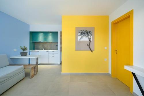 Thassos OLIVIA RESORT في بوتوس: غرفة معيشة مع أريكة وجدار أصفر