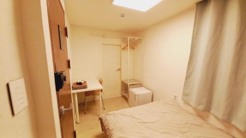 una piccola camera con letto e scrivania di G Yongsan Inn a Seul