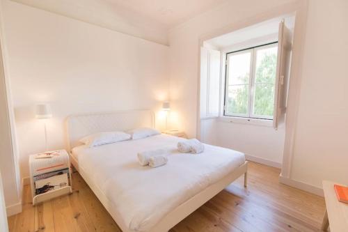 een slaapkamer met een wit bed en 2 handdoeken bij Historical Apartment Santos III in Lissabon