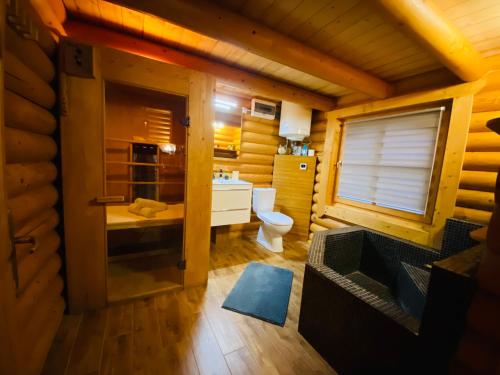 a bathroom in a log cabin with a toilet and a sink at Rönk Vendégház in Tiszaroff