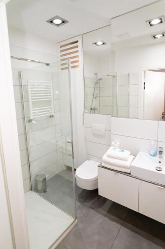 a white bathroom with a toilet and a sink at Triton Apartments in Warsaw
