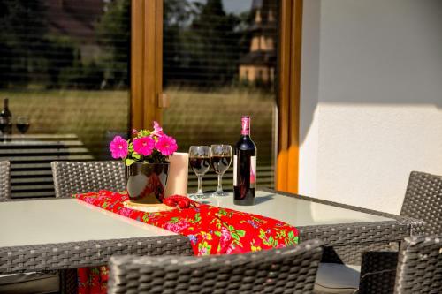 a table with a bottle of wine and flowers on it at Korona Gór - Domki Białka Tatrzańska in Białka Tatrzanska