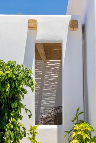 a mirror on the side of a white house with plants at Adama Mykonos Boutique Hotel in Mýkonos City