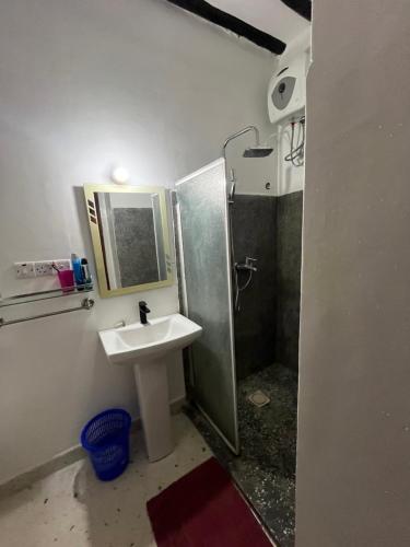 a bathroom with a sink and a shower with a mirror at The cliff room in Pongwe