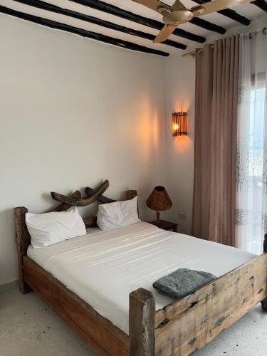 una camera con letto in legno e lenzuola bianche di The cliff room a Pongwe