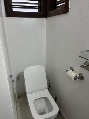 a small bathroom with a toilet and a window at Malcom Ocean View Retreat in Pongwe