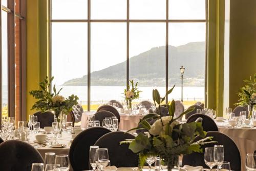 a dining room with tables and chairs and large windows at Slieve Donard in Newcastle