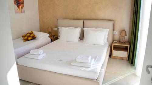 a bedroom with two beds with white sheets and towels at Palm Side Drymades in Dhërmi