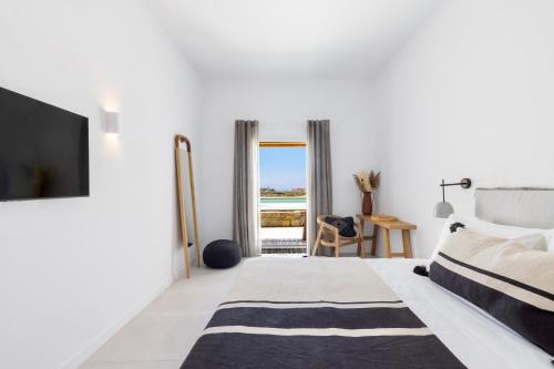 a white bedroom with a bed and a tv at Adama Mykonos Boutique Hotel in Mýkonos City