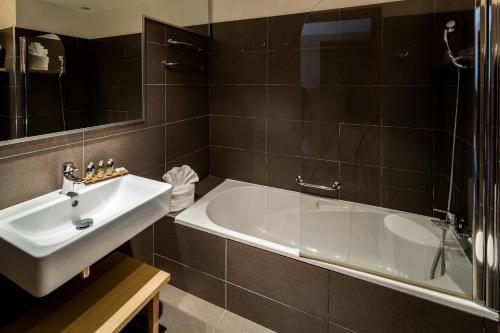 a bathroom with a white tub and a sink at Hôtel Helios & SPA - Ile des Embiez in Six-Fours-les-Plages