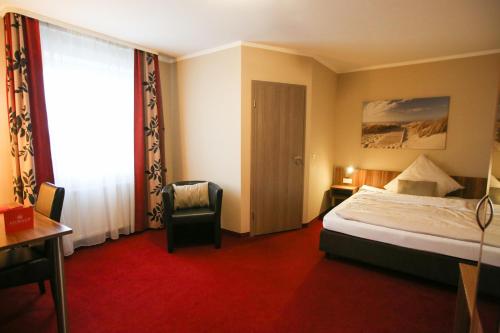 a hotel room with a bed and a chair and a window at Auwald Hotel in Ingolstadt