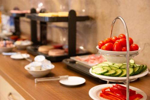 a buffet with bowls of tomatoes and cucumbers on plates at Auwald Hotel in Ingolstadt
