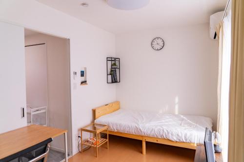 a bedroom with a bed and a clock on the wall at One Point Five in Tokyo