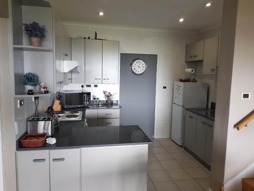 uma cozinha com armários brancos e um relógio na parede em Dieu Donne em Stellenbosch