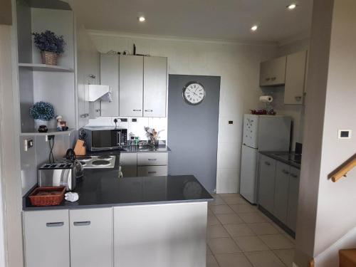 a kitchen with white cabinets and a clock on the wall at Dieu Donne in Stellenbosch
