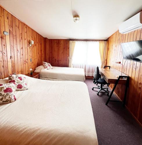 Habitación de hotel con 2 camas y escritorio en Hostal Feliza, en Valdivia