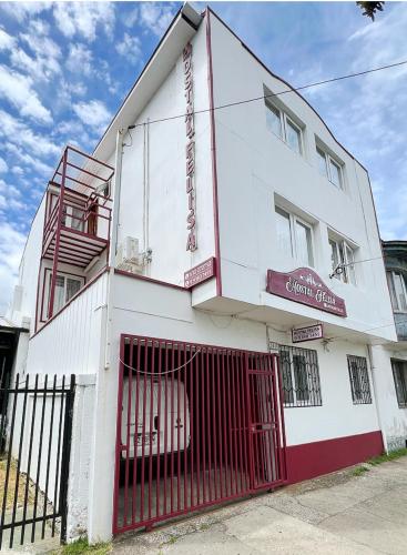 a white building with a red gate in front of it at Hostal Feliza in Valdivia