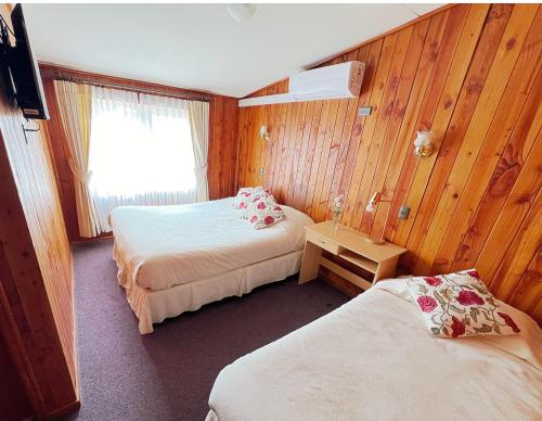 a hotel room with two beds and a window at Hostal Feliza in Valdivia