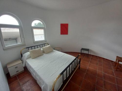 a bedroom with a bed with white sheets and two windows at Apartamento Montemar I REA-MON2 in Castellón de la Plana