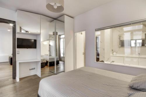 um quarto com uma cama, uma televisão e um espelho em mandar 14 em Paris