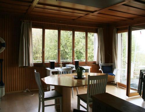 una sala da pranzo con tavolo, sedie e finestre di Haus am Seeufer mit Veranda in natürlicher Umgebung a Güttingen