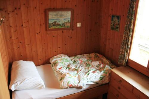 ein kleines Zimmer mit einem Bett in einer Holzwand in der Unterkunft Haus am Seeufer mit Veranda in natürlicher Umgebung in Güttingen