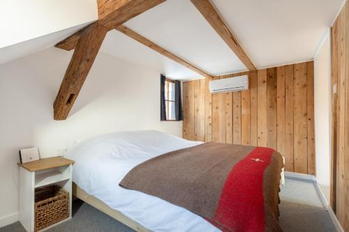 um quarto com uma cama branca e paredes de madeira em Chabi Chalet Gîte au coeur d'Eguisheim em Eguisheim