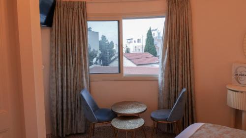 um quarto com duas cadeiras, uma mesa e uma janela em German Colony Apartments em Haifa