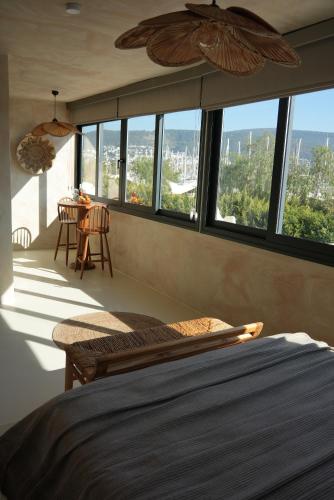 a bedroom with a bed and a table and windows at Noi Hotel Bodrum in Bodrum City