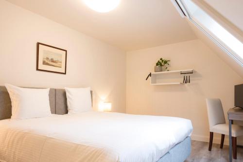 a bedroom with a white bed and a desk at Loweide Lodges & Holiday Homes near Bruges in Oostkamp