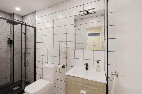 a white tiled bathroom with a toilet and a sink at Apartamentos y lofts en Triana in Seville