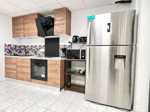 une cuisine avec un réfrigérateur en acier inoxydable et des armoires en bois dans l'établissement Le Grand Penon ~ Logement Spacieux à 6 min du Parc, à Saint-Georges-lès-Baillargeaux
