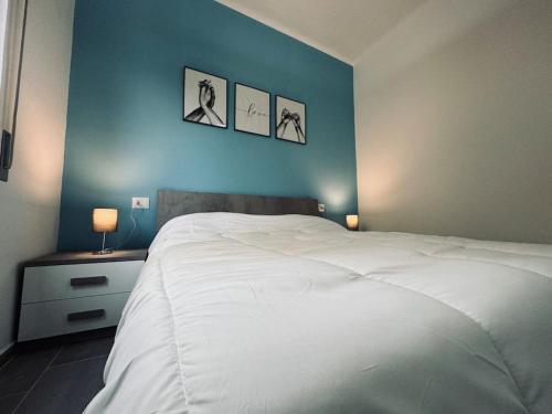 una camera da letto con un letto bianco con tre immagini sul muro di Casa Victoria A due passi dall'Ariston Internet Gratis a Sanremo