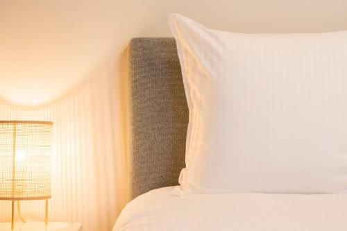 a bed with a white pillow and a chair at Loweide Lodges & Holiday Homes near Bruges in Oostkamp
